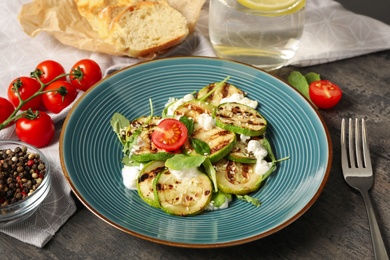 Photo of Delicious grilled zucchini slices served with cottage cheese and tomatoes on grey table, closeup