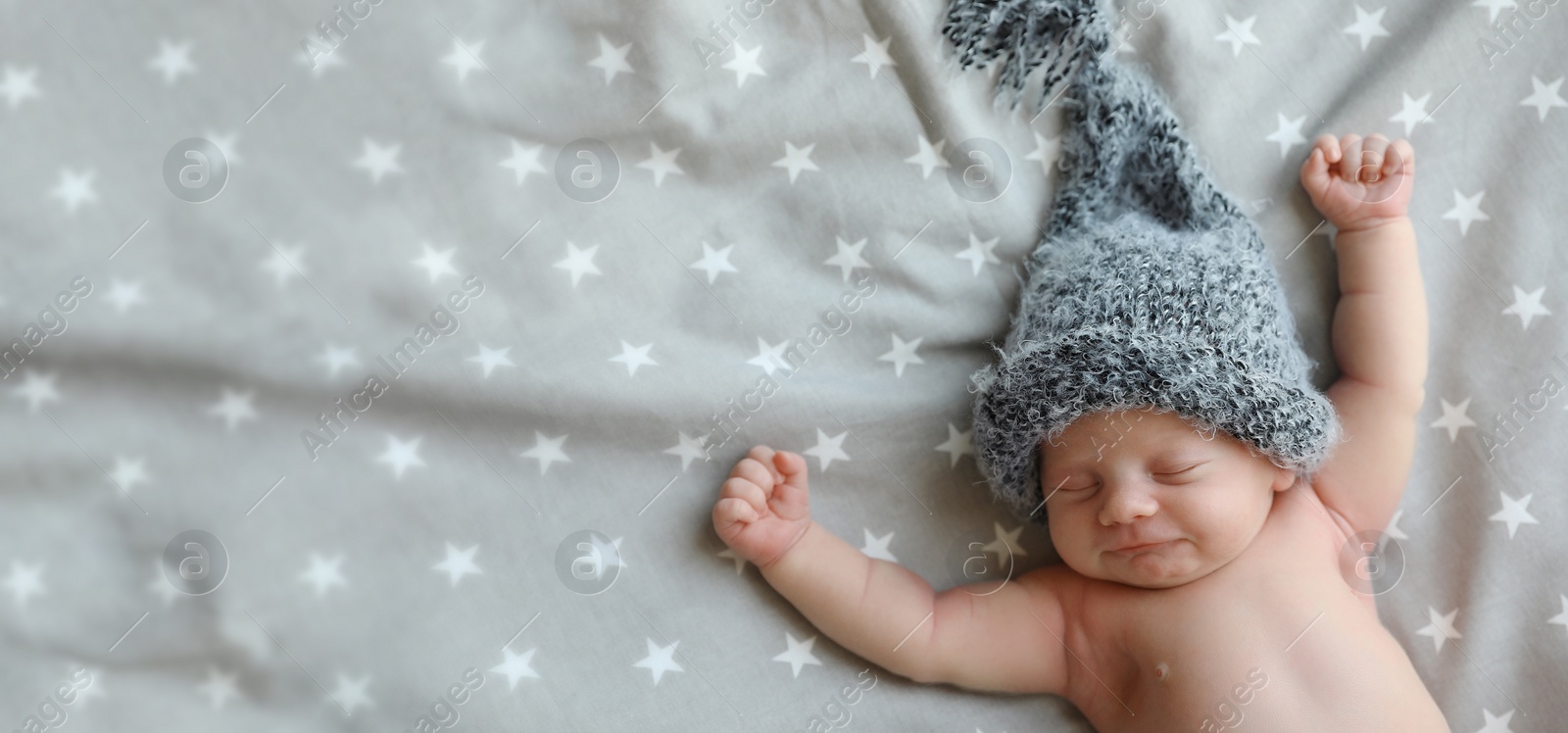 Image of Cute newborn baby in warm hat sleeping on bed, top view with space for text. Banner design