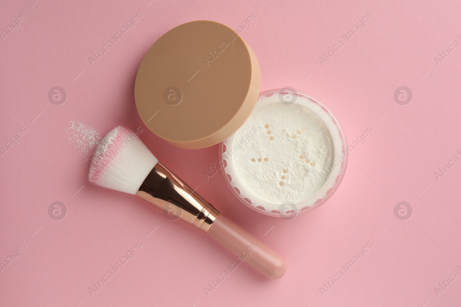 Photo of Rice loose face powder and makeup brush on pink background, flat lay