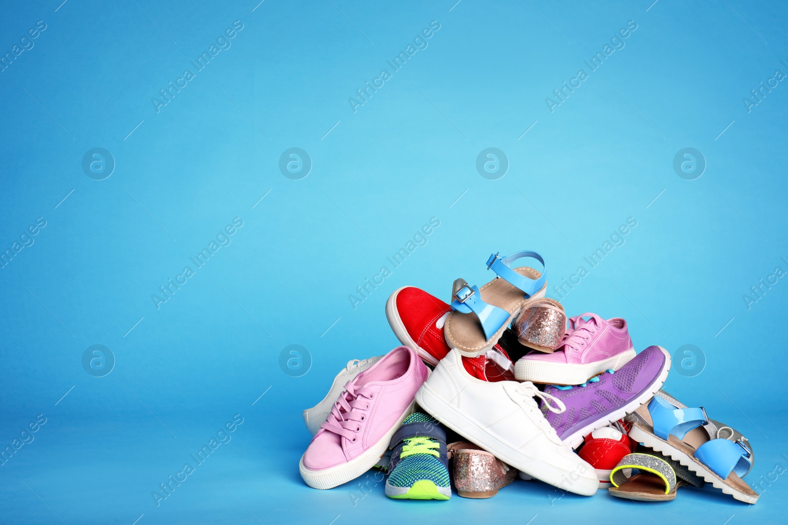 Photo of Heap of different shoes on color background. Space for text