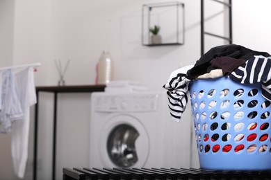 Laundry basket with clothes on black bench in bathroom. Space for text