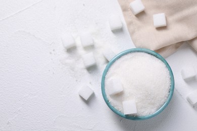 Different types of sugar in bowl on white table, flat lay. Space for text