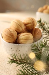 Photo of Delicious nut shaped cookies and fir tree branch on table, closeup