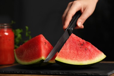 Photo of Woman cutting delicious watermelon on slate board, closeup