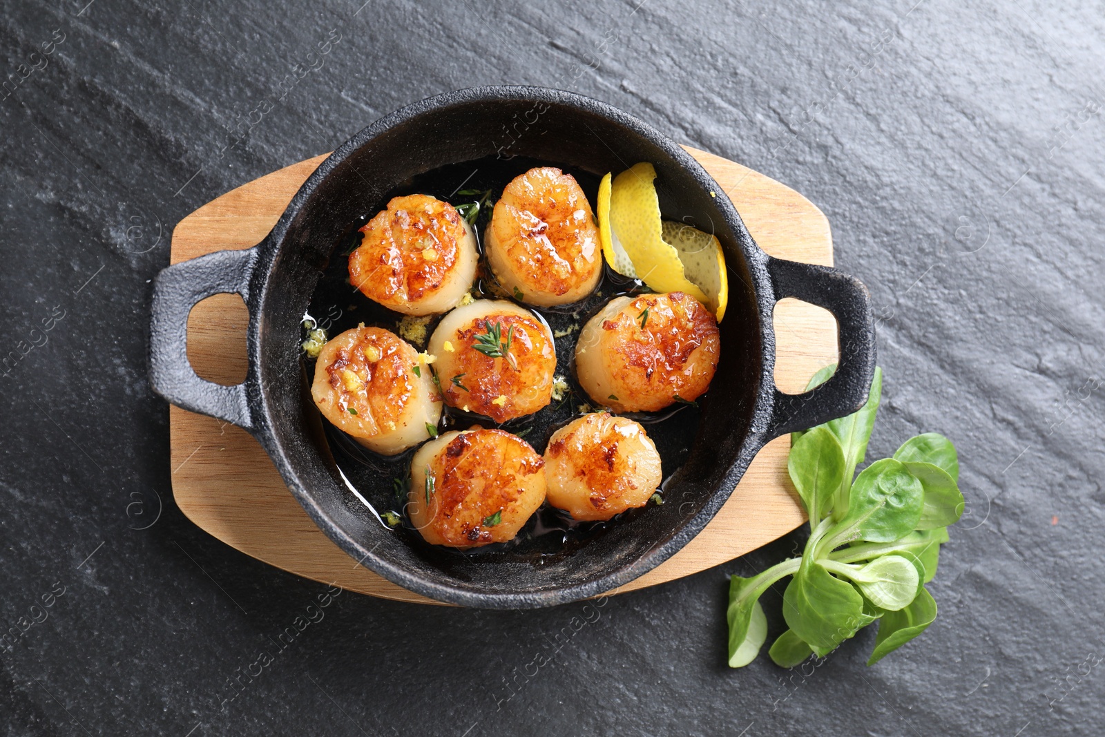 Photo of Delicious fried scallops and corn salad on dark gray textured table, top view