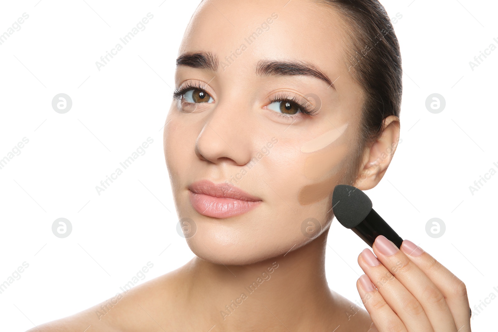 Photo of Young woman applying foundation on her face against white background