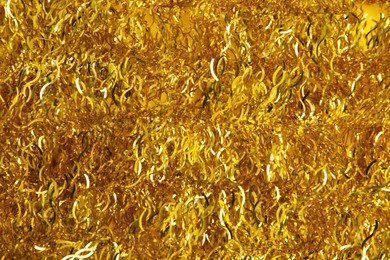 Photo of Shiny golden tinsel as background, top view