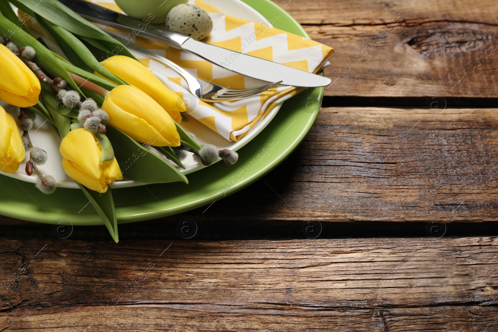 Photo of Festive Easter table setting with beautiful tulips and willow branches, closeup