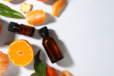 Photo of Aromatic tangerine essential oil in bottles and citrus fruits on white table, flat lay. Space for text