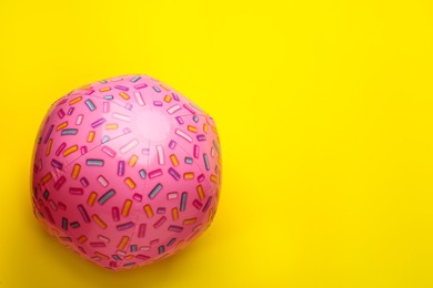 Photo of Bright beach ball on yellow background, top view. Space for text