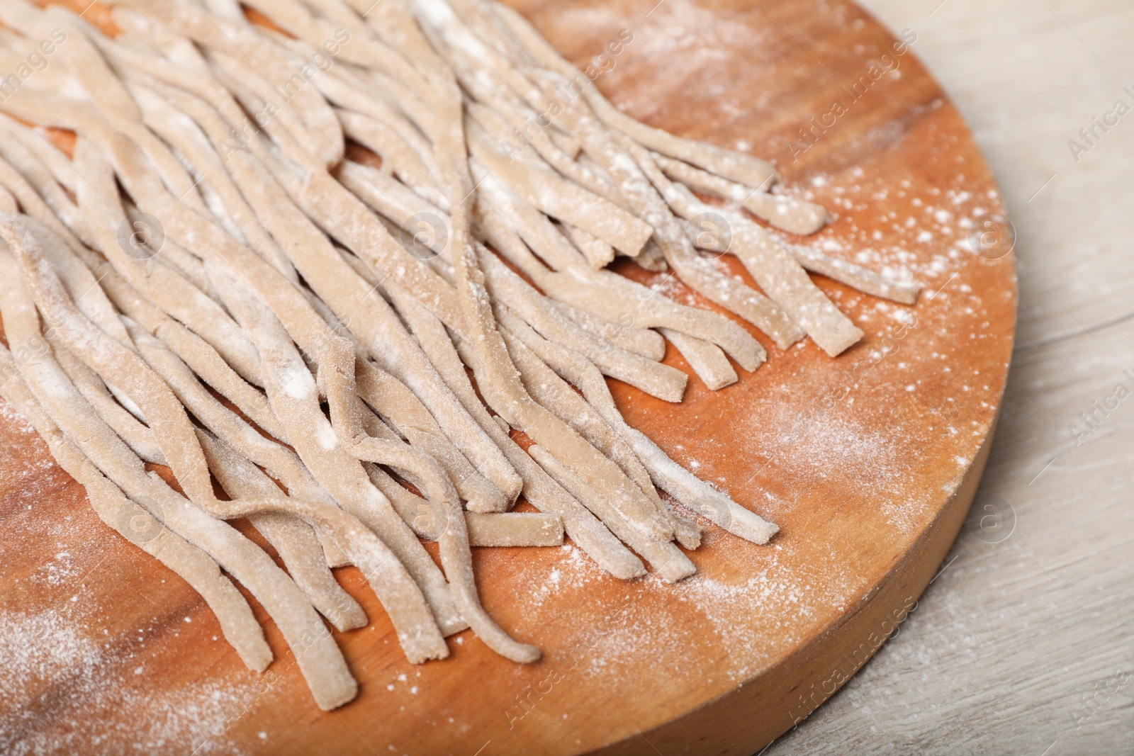 Photo of Uncooked homemade soba (buckwheat noodles) on wooden table, closeup