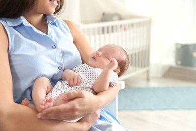 Young woman with her newborn baby at home, closeup. Space for text