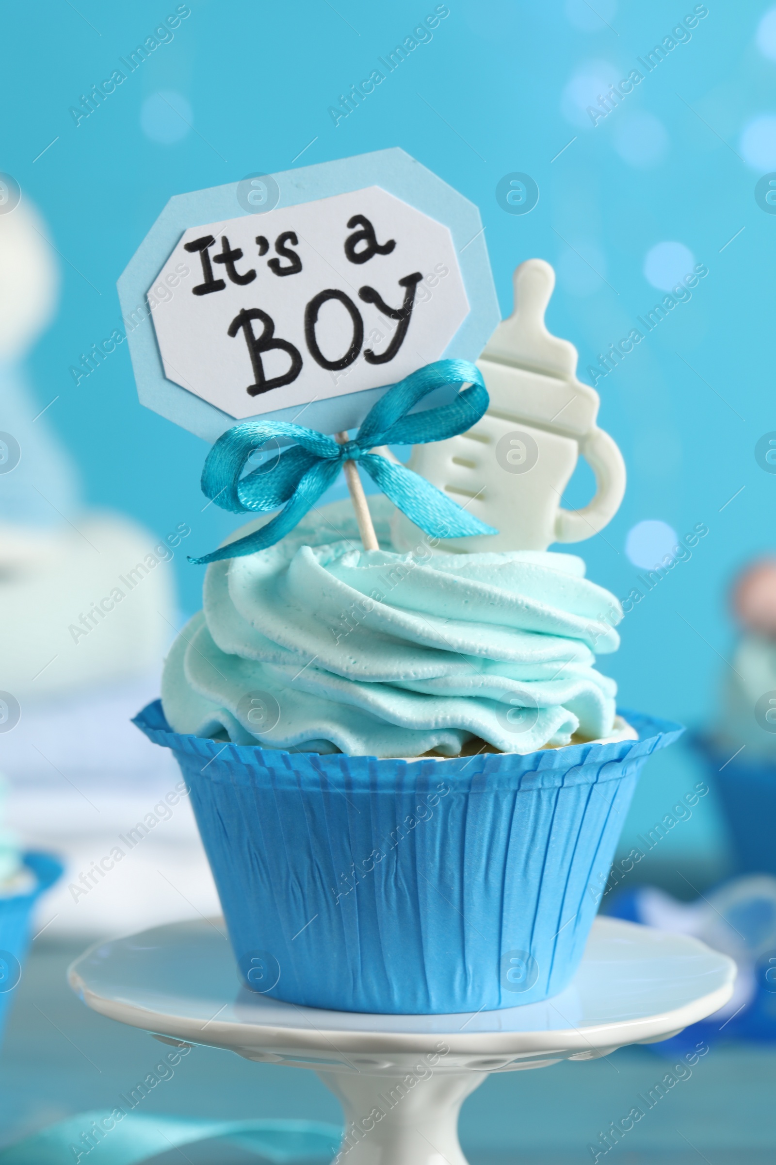Photo of Beautifully decorated baby shower cupcake for boy with cream and topper on light blue background, closeup