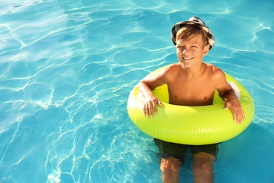 Photo of Happy cute boy with inflatable ring in swimming pool