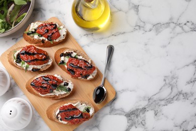 Photo of Delicious bruschettas with sun-dried tomatoes, cream cheese, balsamic vinegar and ingredients on white marble table, flat lay. Space for text