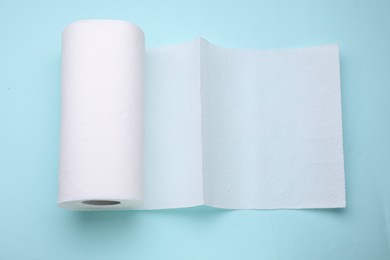 Photo of Roll of tissue towels on light blue background, top view