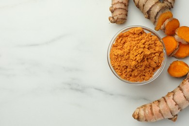 Photo of Aromatic turmeric powder and raw roots on white marble table, flat lay. Space for text
