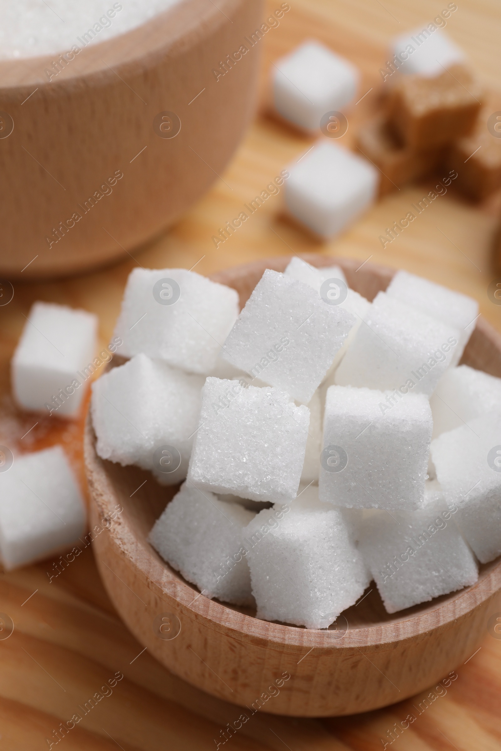 Photo of White sugar cubes in bowl on table, above view