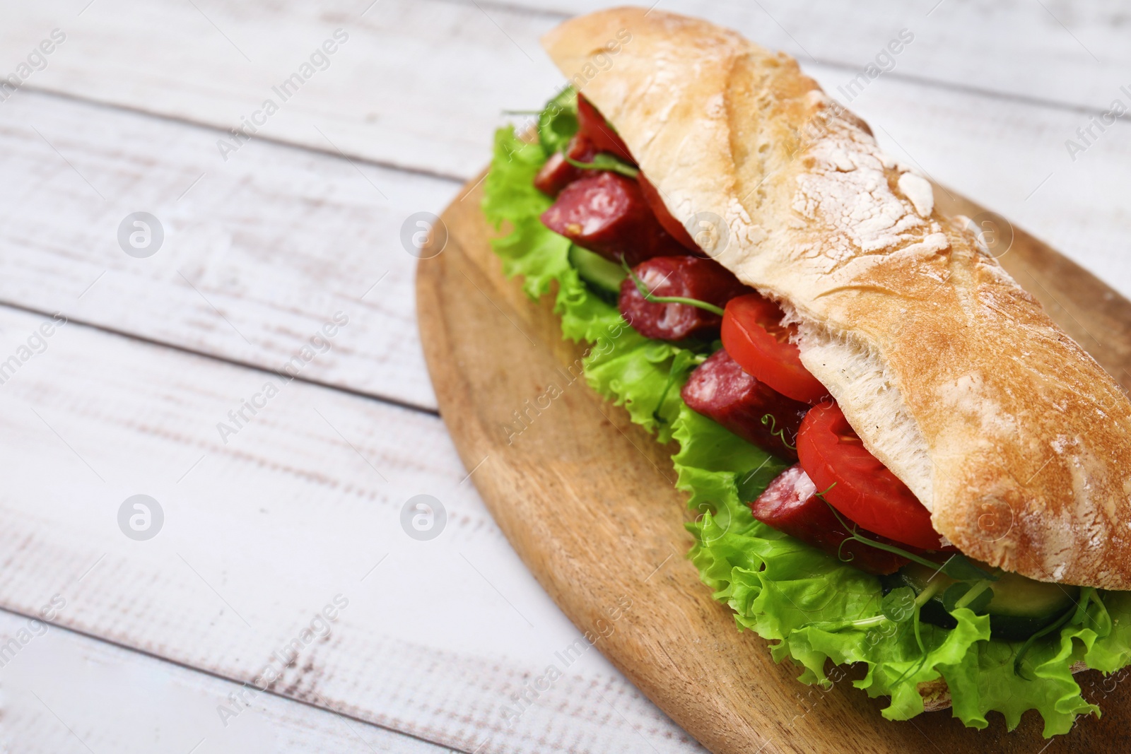 Photo of Delicious sandwich with sausages and vegetables on white wooden table, closeup. Space for text