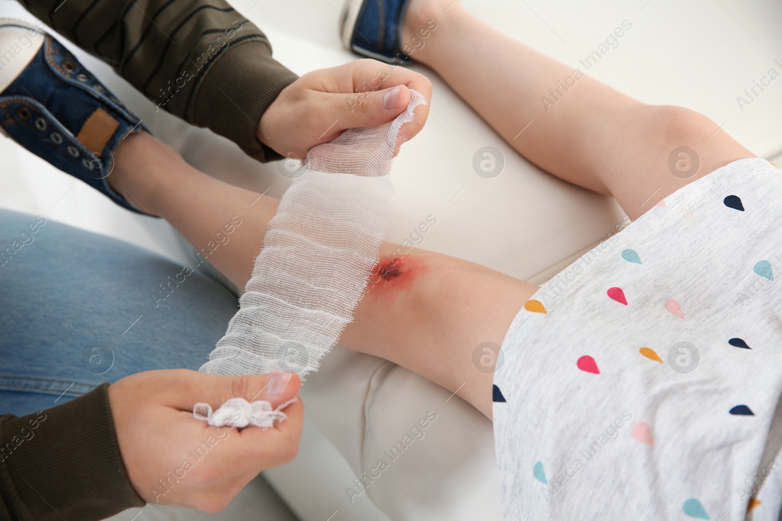 Photo of Father applying bandage on daughter's injured knee at home, closeup. First aid