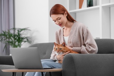 Photo of Woman stroking cat while working on sofa at home