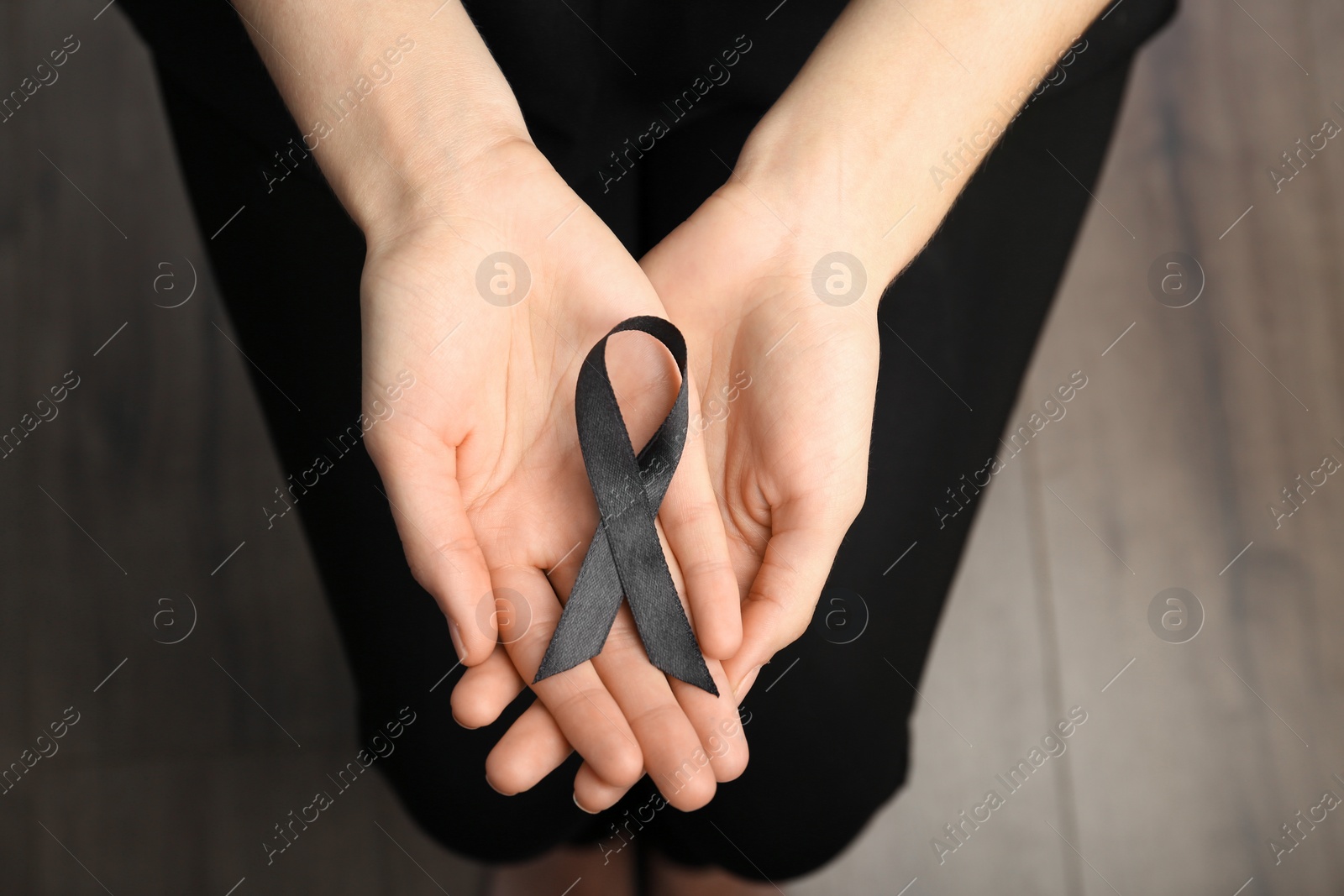 Photo of Woman holding black ribbon, closeup. Funeral symbol