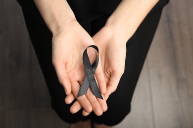 Photo of Woman holding black ribbon, closeup. Funeral symbol