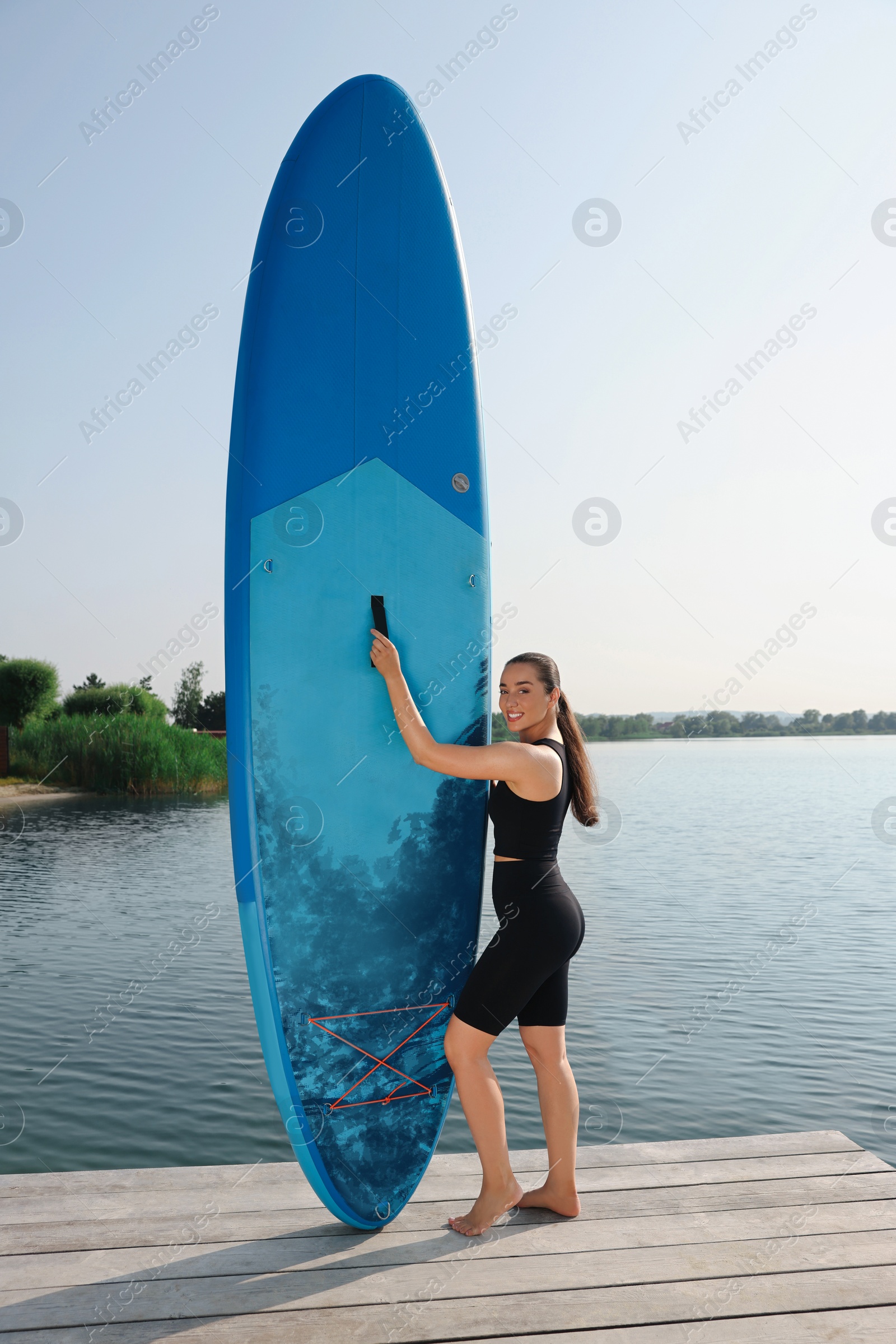 Photo of Woman standing near SUP board on pier