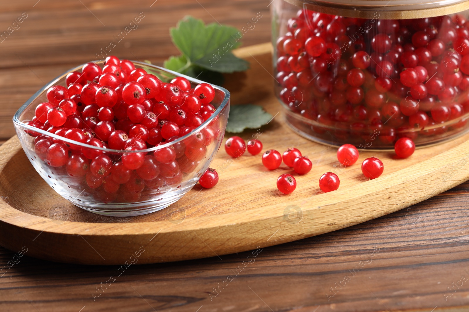 Photo of Ripe red currants and leaves on wooden table