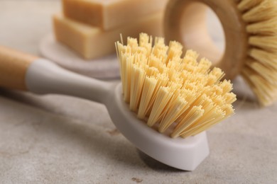 Photo of Cleaning brushes and soap bars on light grey table, closeup