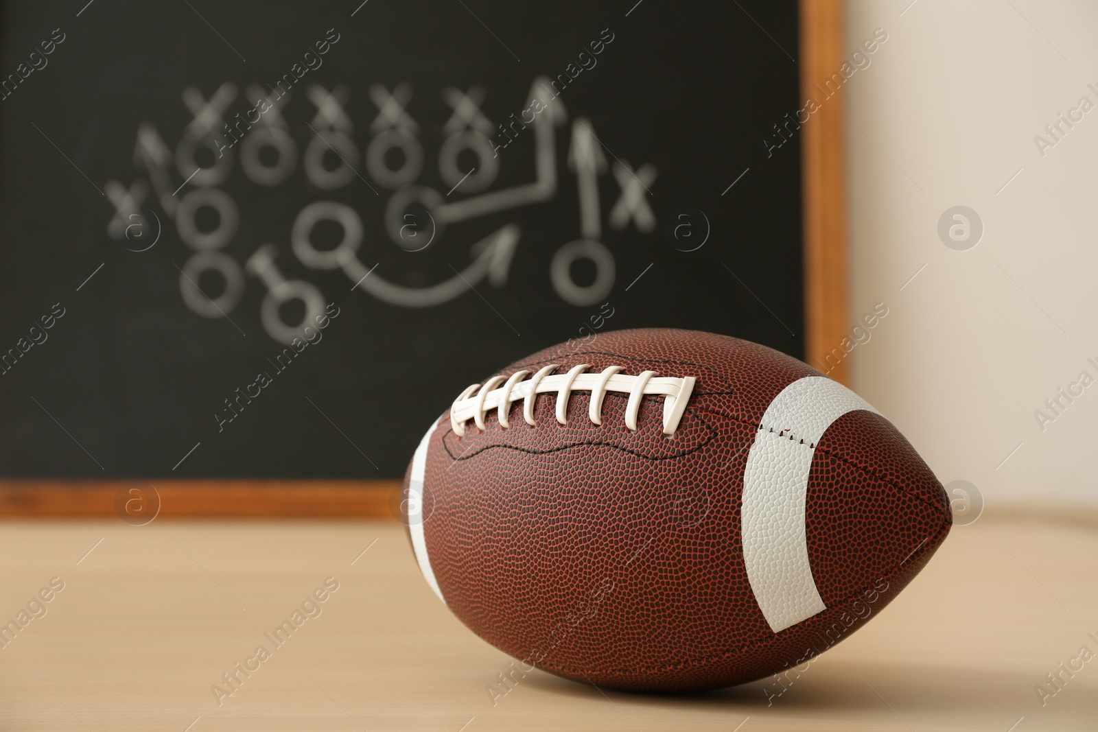 Photo of Rugby ball near chalkboard with football game scheme on table. Space for text