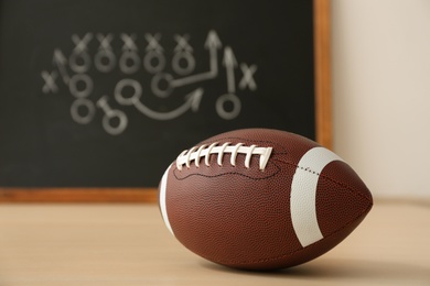 Photo of Rugby ball near chalkboard with football game scheme on table. Space for text