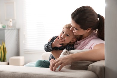 Photo of Mother with her cute little daughter on sofa at home, space for text