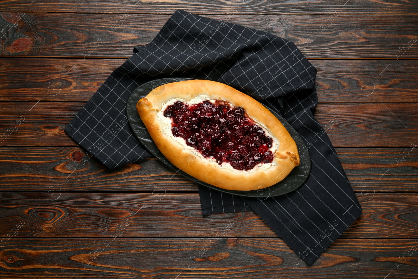 Photo of Delicious sweet cottage cheese pastry with cherry jam on wooden table, top view