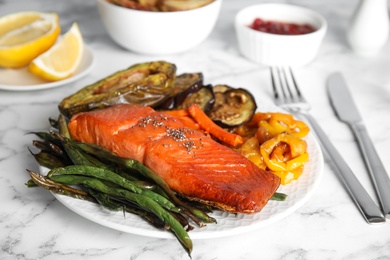 Tasty cooked salmon and vegetables served on white marble table. Healthy meals from air fryer