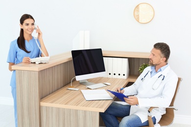 Photo of Doctor and medical assistant working in clinic. Health care service