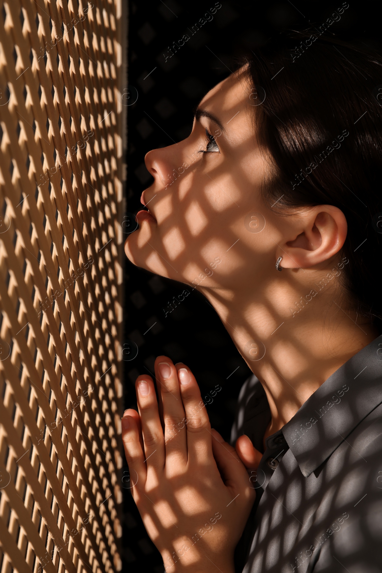 Photo of Woman praying to God during confession in booth