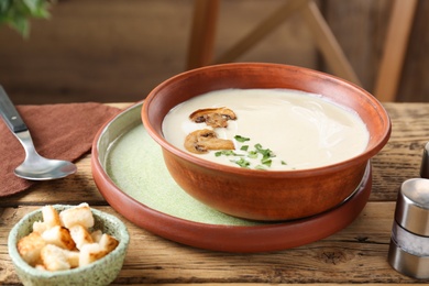 Photo of Delicious cream soup with mushrooms on wooden table