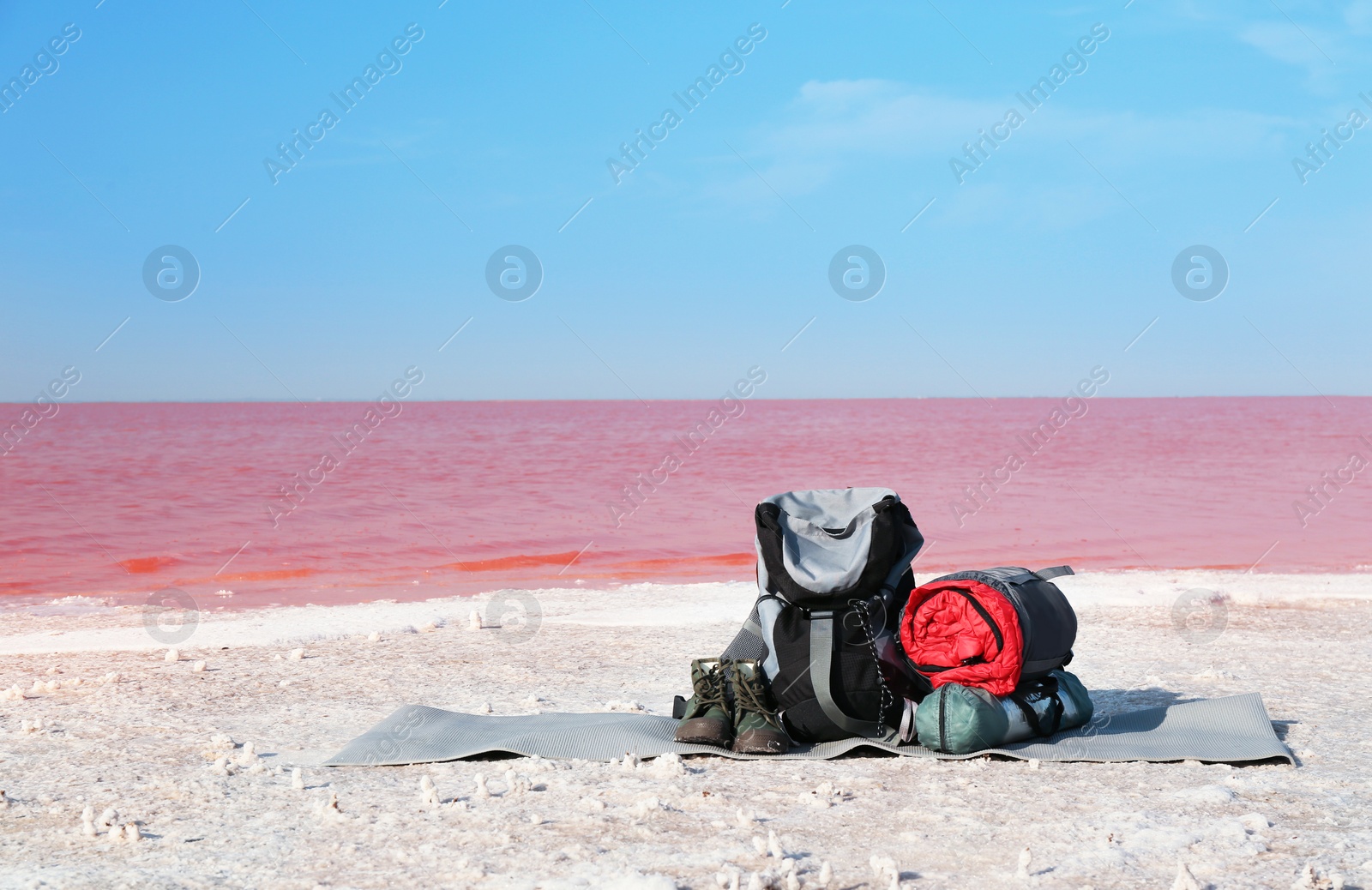 Photo of Set of camping equipment with sleeping bag on coast of pink lake