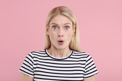 Portrait of surprised woman on pink background