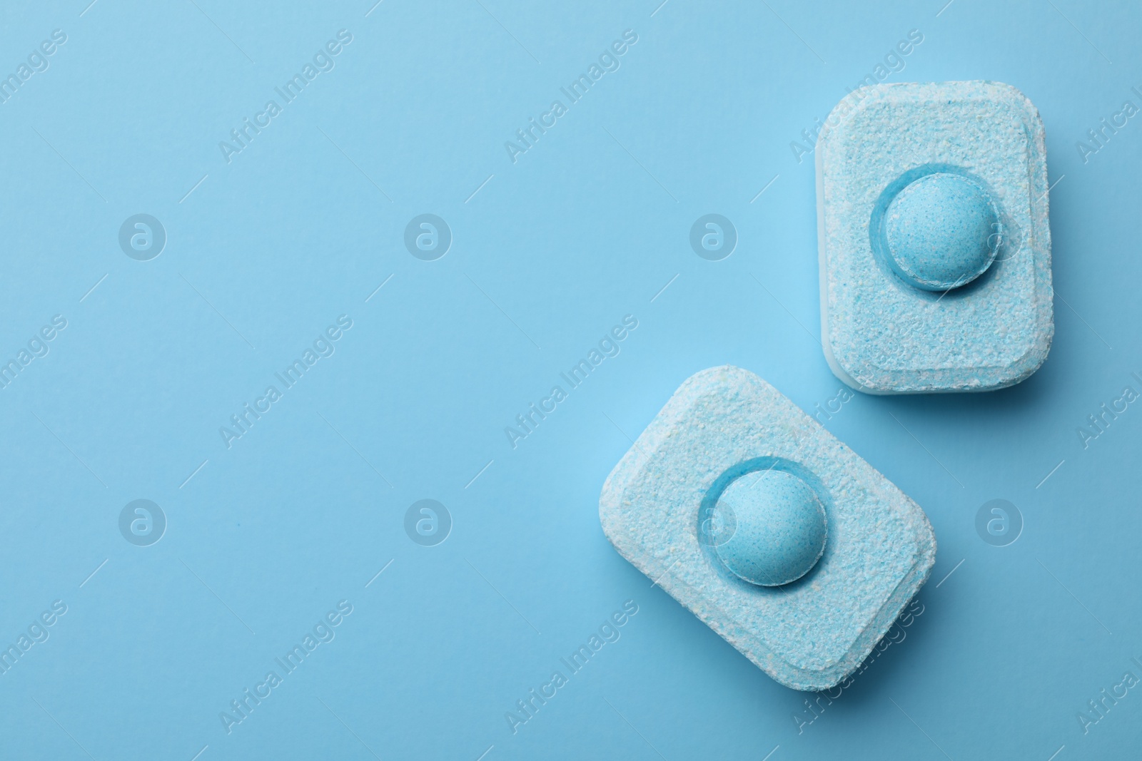 Photo of Water softener tablets on light blue background, flat lay. Space for text