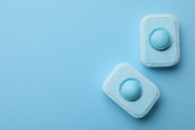 Photo of Water softener tablets on light blue background, flat lay. Space for text