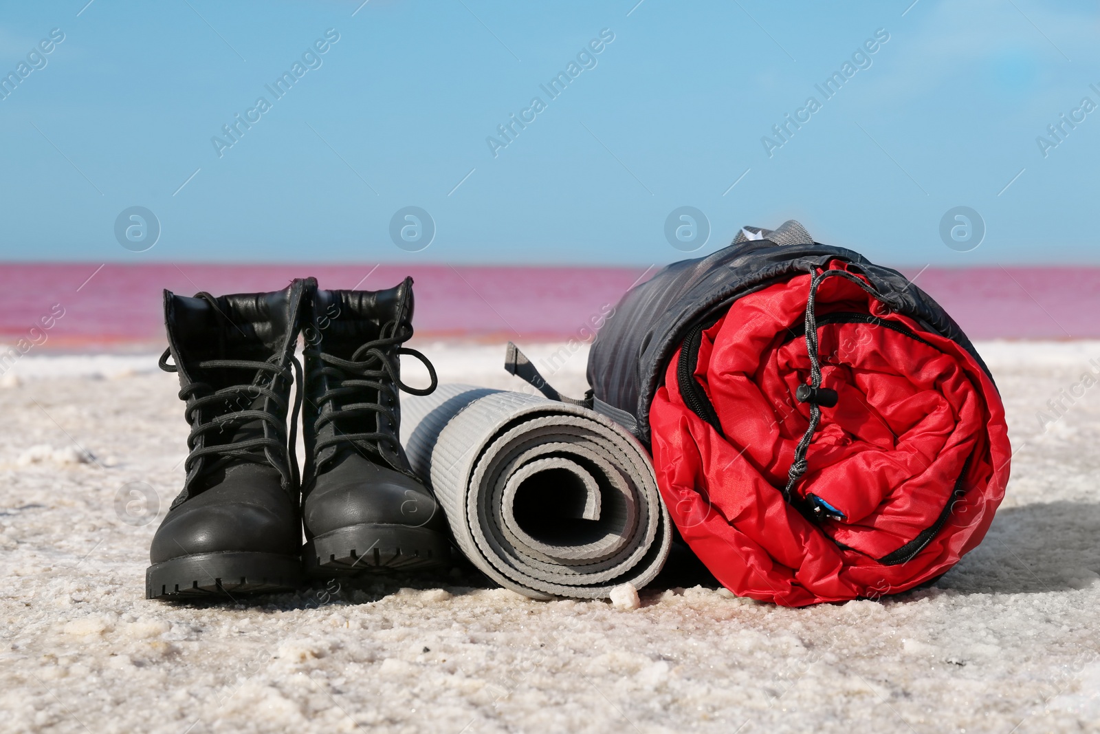 Photo of Set of camping equipment with sleeping bag on coast of pink lake