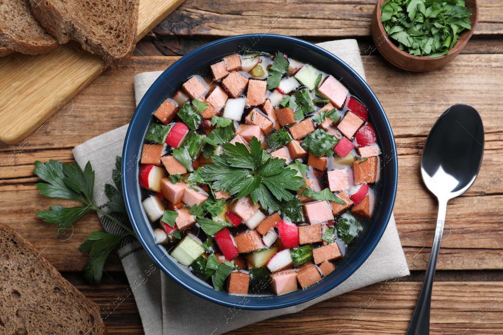 Photo of Delicious cold okroshka with kvass served on wooden table, flat lay. Traditional Russian summer soup