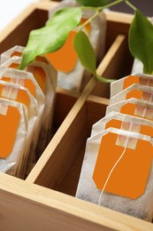 Photo of Paper tea bags with tags in wooden box , closeup
