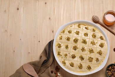 Photo of Making delicious baklava. Raw dough with pistachios and honey on wooden table, flat lay. Space for text.