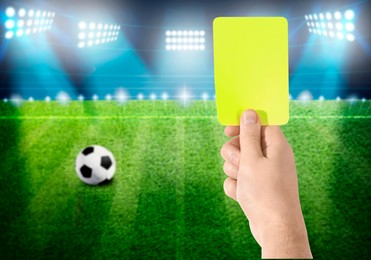 Referee holding yellow card at stadium, closeup