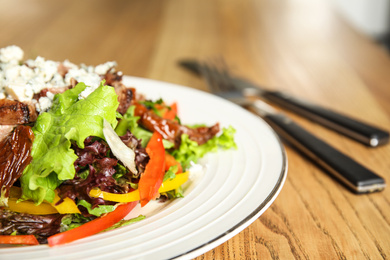 Photo of Delicious salad with roasted meat and vegetables served on wooden table, closeup