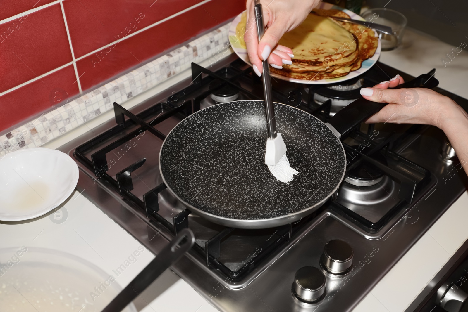 Photo of Woman greasing frying pan on stove in kitchen, closeup