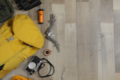 Flat lay composition with different camping equipment on wooden background, space for text. Traveler set